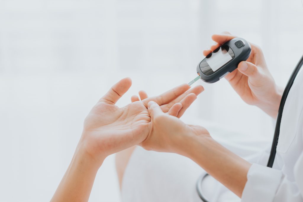 Doctor use glucosmeter checking blood sugar level from patient h